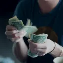 A young woman counting dollar bills.