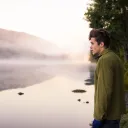 Um jovem olhando para um lago.