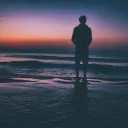 Um homem à beira de um lago ao pôr do sol.