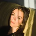 A woman sitting on a couch while her head is resting on cushion.