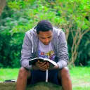 A man sitting on a bench reading a Bible.