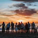 A big family gathering at the beach at sundown.