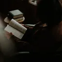 A sitting in a chair reading a Bible.