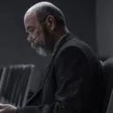 A man sitting in hall with chairs looking at notes.