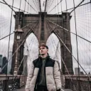 A man walking on the Brooklyn Bridge.