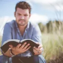 A man reading a Bible outside.