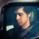 Reflection of a man in a car side mirror.