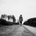 A woman walking on a dirt road.