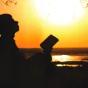 A person holding a Bible and looking up to the sky.