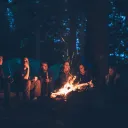 A group of young people around a campfire at night.