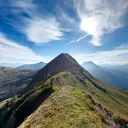 a green mountain beneath a cloudy blue sky