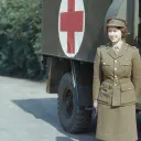 A photo of a young Queen Elizabeth standing in front of an army ambulance,