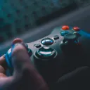 A pair of hands holding a gaming controller above a laptop keyboard