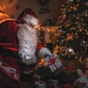 Santa Claus putting gifts under a Christmas tree.