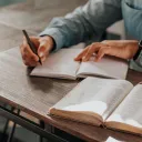 A person taking notes with a Bible open