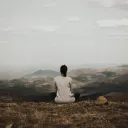 A woman sitting beside herself looking out over a vista.