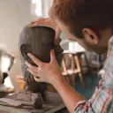 A sculpture forming a human head out of clay.