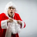 A man putting on a Santa Claus costume.