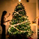 a woman standing in a dark room in front of a glowing Christmas tree