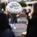 A person hold a balloon that says "Happy Birthday to you"