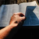A man turning pages of a Bible.