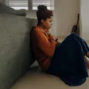 A woman sitting on the floor in thought.