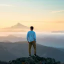 A young man standing on a rock looking out over a vista.