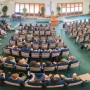a large group of people seated in a semicircle indoors