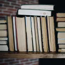 several books stacked on a wooden shelf
