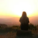 a woman looking at the sunset in the distant hills