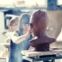 A woman sculpting a clay head.