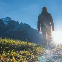A person walking up a path with the sun in front of them.