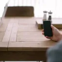 Sitting at table working on laptop and viewing smartphone.