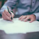 A man writing with a pencil on paper.