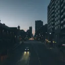 A car driving down a dark street in a big city.