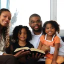 A young family reading Bible to children.