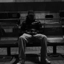 A person sitting along on a bench.