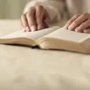Older hands on top of a Bible.
