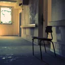 A lone student desk in a old run down school hallway.