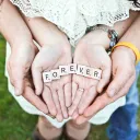 A young married coupling holding in the hands Scrabble letters that spell FOREVER
