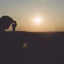 A man sitting with the sun in the background.