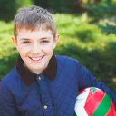 A young boy holding a ball and smiling.