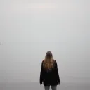 A woman standing by herself looking up.