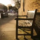 A empty bench on a sidewalk.