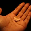 hand holding a single penny