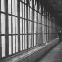 A long hall lined by windows with people walking in the distance.