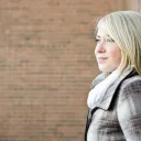 A teenage girl standing by a brickwall.