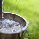 Water pouring into a wood bucket.