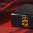 A Bible sitting on a red piece of cloth.
