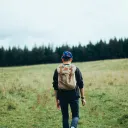 A young man walking up a hill with a backpack.